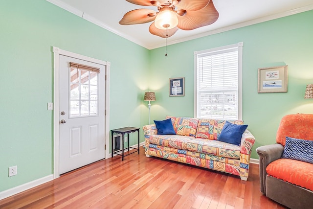 living area with baseboards, crown molding, ceiling fan, and wood finished floors