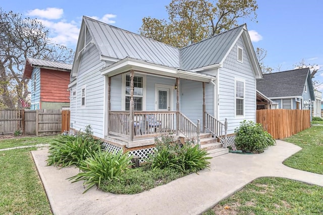 view of front of home featuring metal roof, covered porch, a standing seam roof, and fence