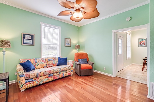 living area with a healthy amount of sunlight, wood-type flooring, ceiling fan, and ornamental molding