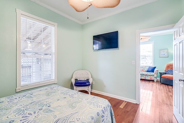 bedroom with baseboards, wood finished floors, a ceiling fan, and ornamental molding