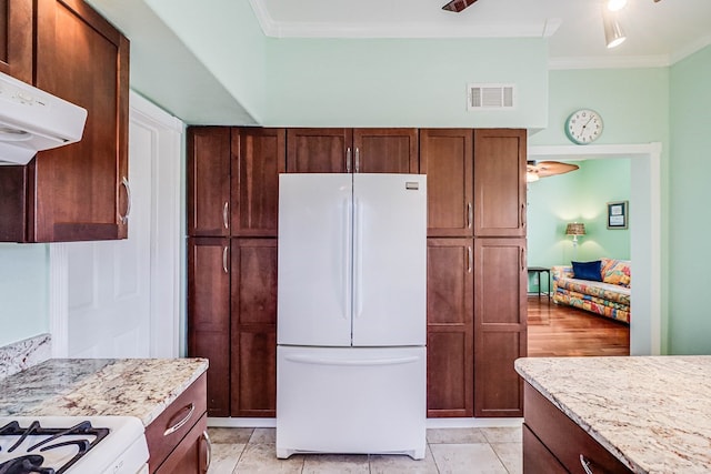 kitchen featuring light stone countertops, visible vents, freestanding refrigerator, ornamental molding, and exhaust hood