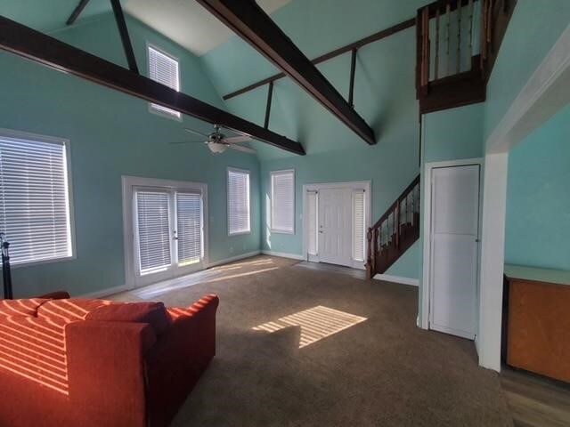 unfurnished living room featuring stairway, high vaulted ceiling, carpet, and baseboards