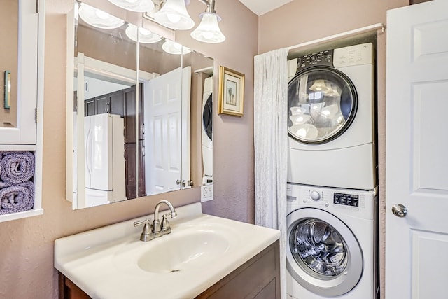 clothes washing area with a sink, a textured wall, laundry area, and stacked washing maching and dryer