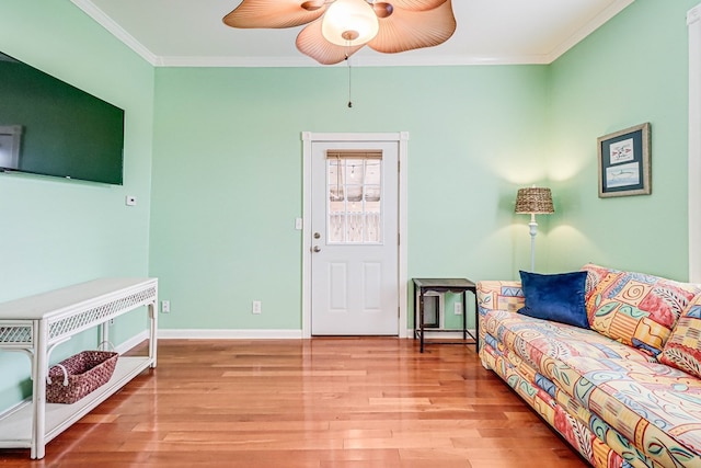 living room with baseboards, wood finished floors, a ceiling fan, and ornamental molding