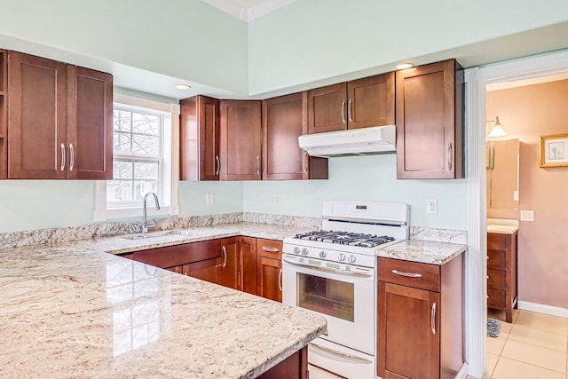 kitchen with under cabinet range hood, a sink, light stone counters, and white gas range oven