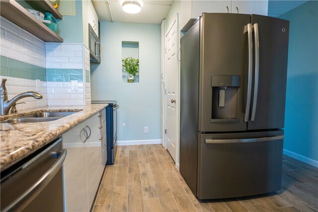 4334 E Ocean Dr Unit 306, Corpus Christi, TX 78404 - kitchen featuring appliances with stainless steel finishes, light wood-type flooring, decorative backsplash, light stone counters, and white cabinets