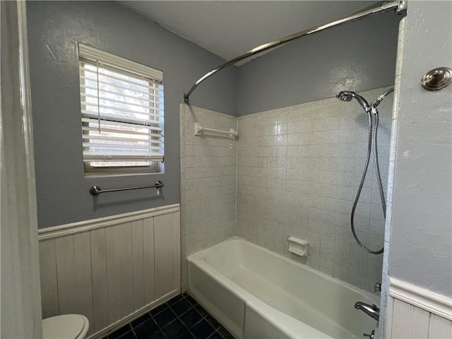 bathroom with toilet, tiled shower / bath combo, and tile patterned floors