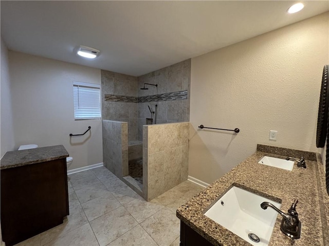 bathroom with tile patterned flooring, vanity, toilet, and tiled shower