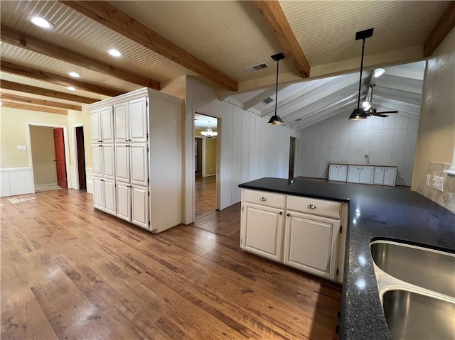 kitchen with ceiling fan with notable chandelier, lofted ceiling with beams, light hardwood / wood-style floors, white cabinetry, and hanging light fixtures