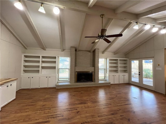 unfurnished living room featuring plenty of natural light, ceiling fan, a fireplace, and dark wood-type flooring