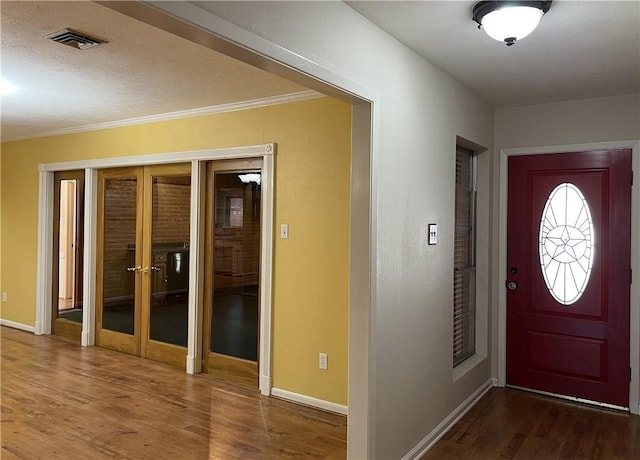 entrance foyer with crown molding, hardwood / wood-style floors, and french doors