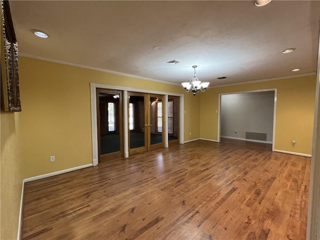 spare room featuring wood-type flooring, an inviting chandelier, and ornamental molding