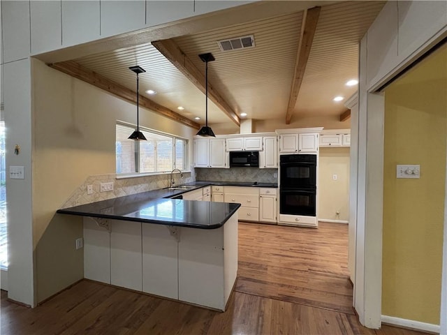 kitchen with kitchen peninsula, sink, white cabinets, and decorative light fixtures