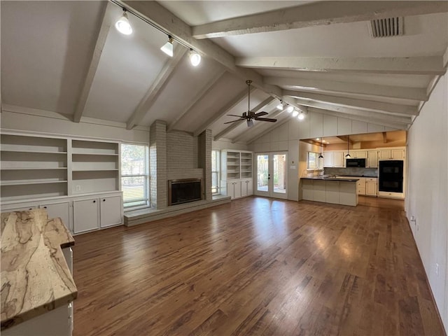 unfurnished living room featuring french doors, ceiling fan, lofted ceiling with beams, a fireplace, and dark hardwood / wood-style floors