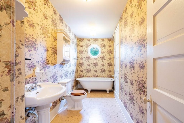 711 E Lott St, Beeville, TX 78102 - full bathroom with wallpapered walls, a freestanding bath, toilet, baseboards, and a sink