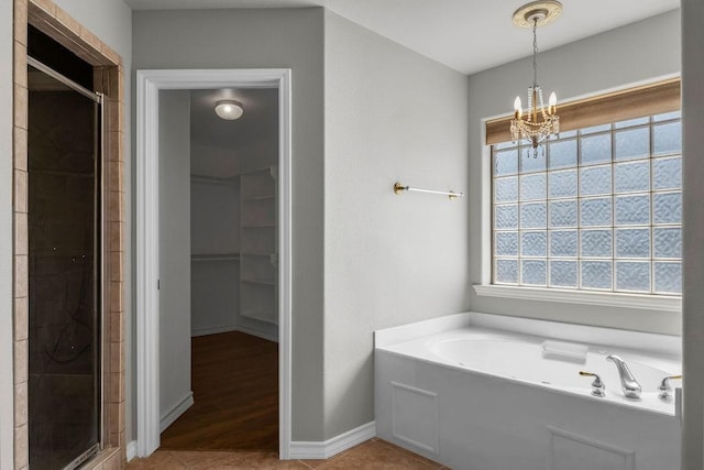 bathroom featuring a chandelier, a garden tub, baseboards, tile patterned floors, and a stall shower