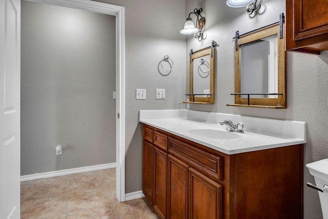 bathroom with tile patterned flooring, baseboards, vanity, and toilet