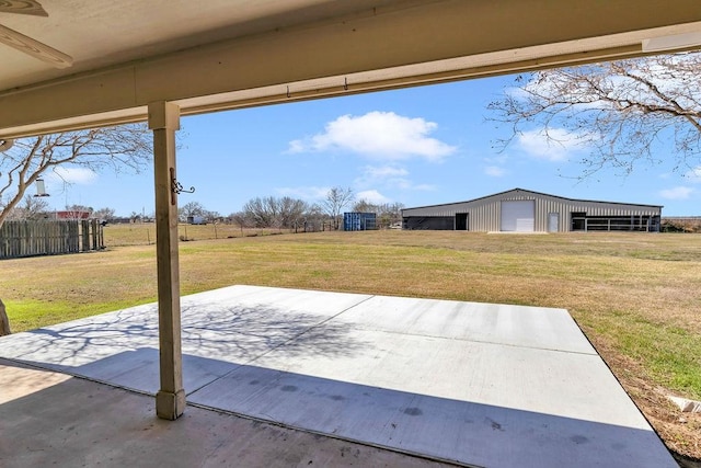 view of patio with an outbuilding, a pole building, a detached garage, and fence