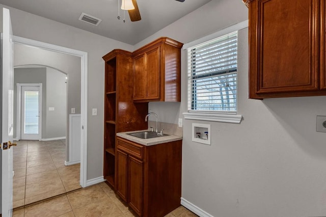 kitchen featuring arched walkways, a sink, visible vents, light countertops, and a wealth of natural light