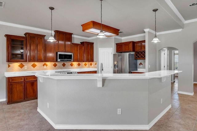 kitchen with arched walkways, stainless steel appliances, light countertops, and a large island with sink