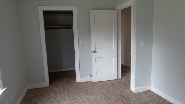 unfurnished bedroom with a closet and light colored carpet
