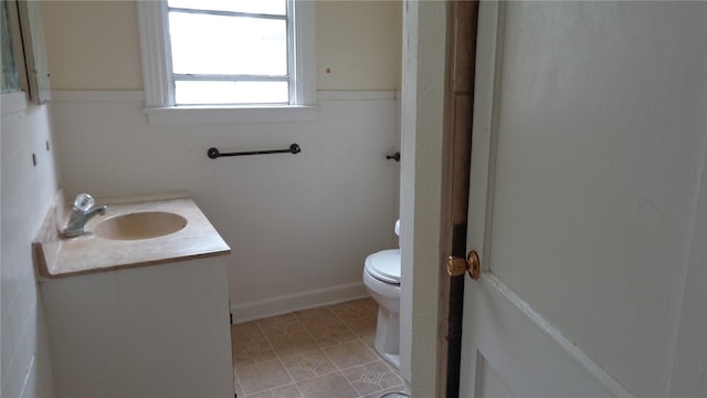 bathroom featuring vanity, toilet, and tile walls