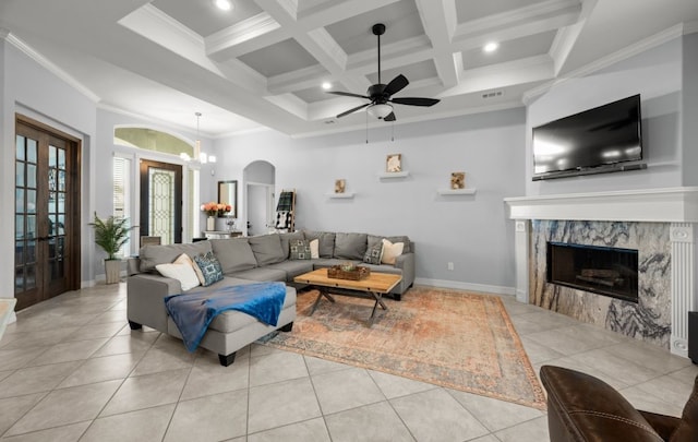 living room featuring beamed ceiling, crown molding, coffered ceiling, light tile patterned floors, and ceiling fan with notable chandelier