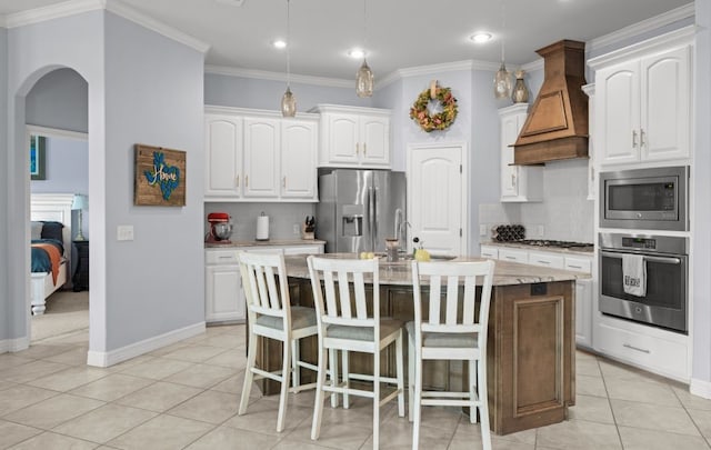 kitchen featuring premium range hood, white cabinets, a center island with sink, and stainless steel appliances