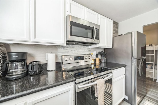 123 E Cora Lee Dr Unit 301, South Padre Island, TX 78597 - kitchen with stainless steel appliances, white cabinetry, decorative backsplash, dark stone countertops, and light wood-type flooring