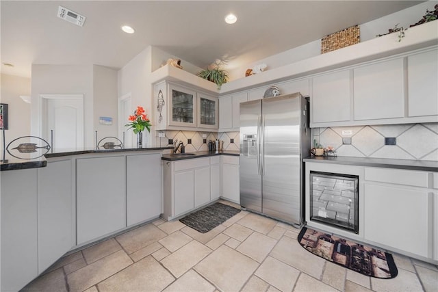 113 Sea Air Ln, Port Aransas, TX 78373 - kitchen featuring stainless steel fridge with ice dispenser, decorative backsplash, dark countertops, white cabinets, and recessed lighting