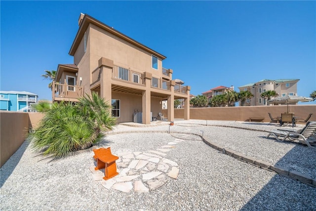 113 Sea Air Ln, Port Aransas, TX 78373 - rear view of house with stucco siding, a balcony, a patio, and a fenced backyard