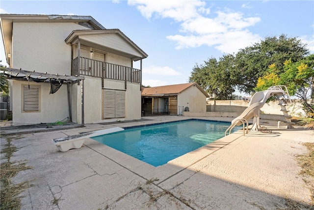 view of pool with a water slide, a diving board, and a patio