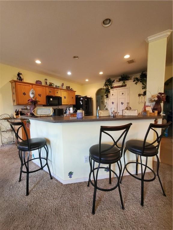 2602 Whirlwind St, Corpus Christi, TX 78414 - kitchen with black appliances, carpet floors, dark countertops, recessed lighting, and a breakfast bar area
