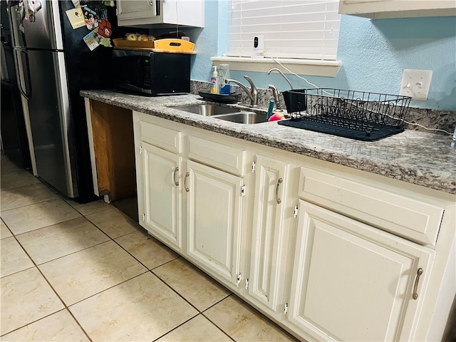 kitchen featuring light tile patterned flooring, stainless steel fridge, light stone countertops, and sink