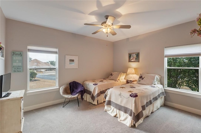 bedroom with light carpet, a ceiling fan, and baseboards