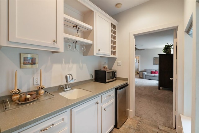 kitchen with light carpet, open shelves, stainless steel microwave, a sink, and white cabinetry