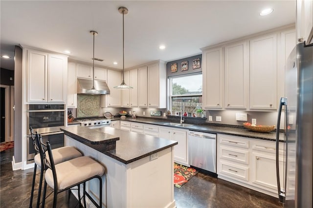 kitchen featuring a sink, stainless steel appliances, under cabinet range hood, dark countertops, and a center island