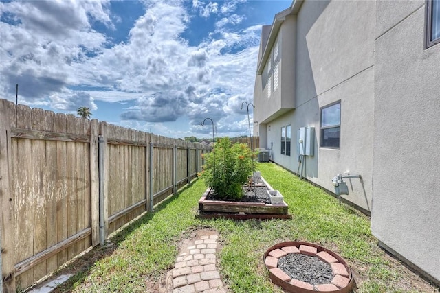 view of yard with a vegetable garden, central AC, and a fenced backyard