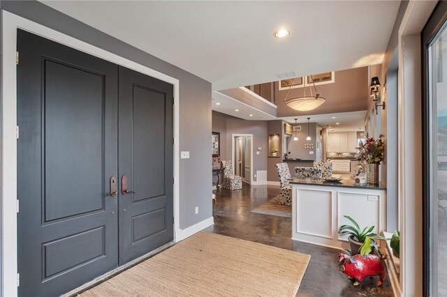 foyer entrance with recessed lighting, baseboards, and finished concrete floors