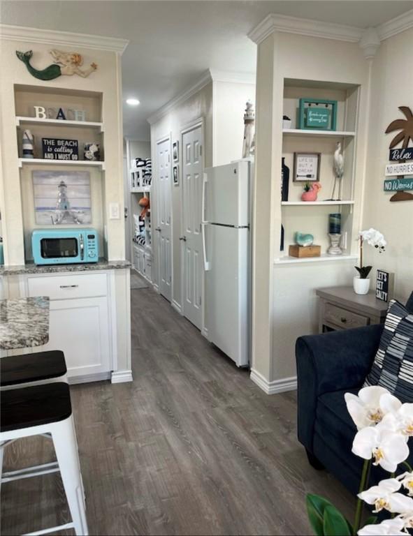 3938 Surfside Blvd Unit 1326, Corpus Christi, TX 78402 - kitchen with white appliances, crown molding, white cabinets, dark wood-style flooring, and light stone counters