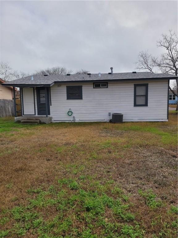 back of house featuring a lawn and central air condition unit