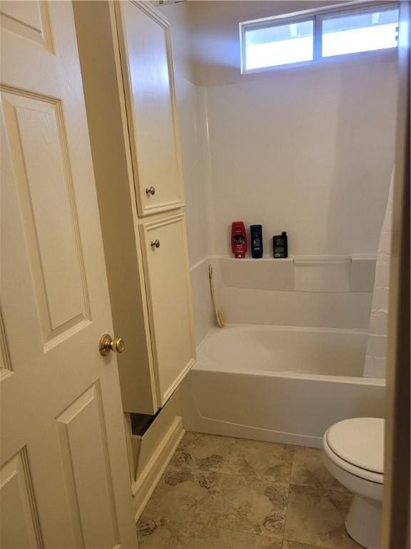 bathroom with a tub to relax in and toilet