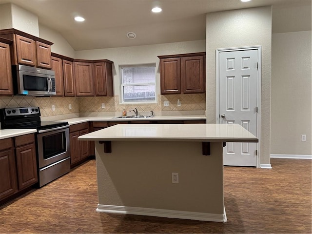 kitchen with a breakfast bar area, stainless steel appliances, sink, and a center island