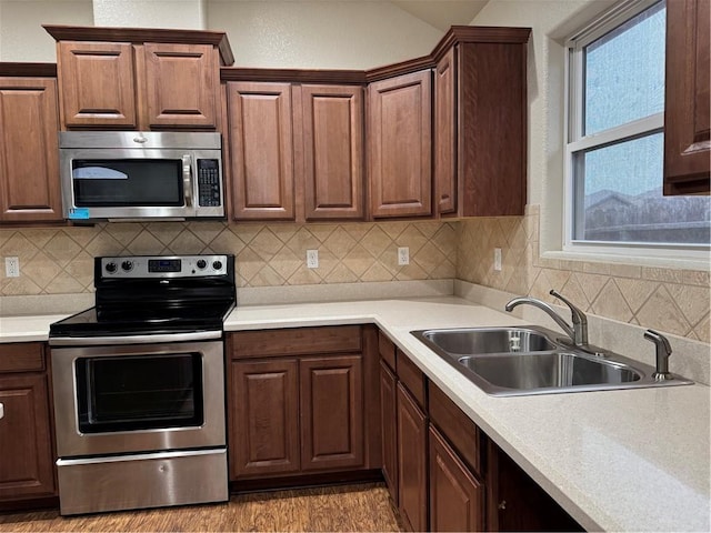 kitchen with sink, stainless steel appliances, and hardwood / wood-style flooring