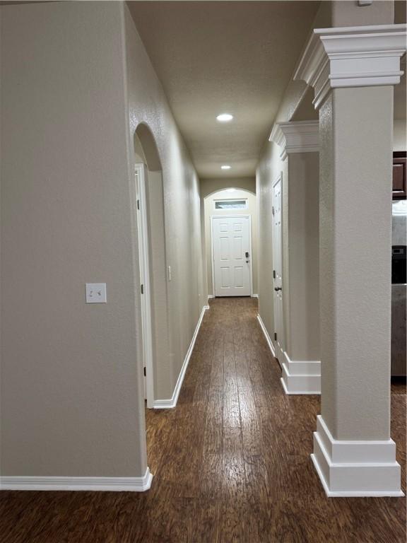 hallway featuring decorative columns and dark hardwood / wood-style floors