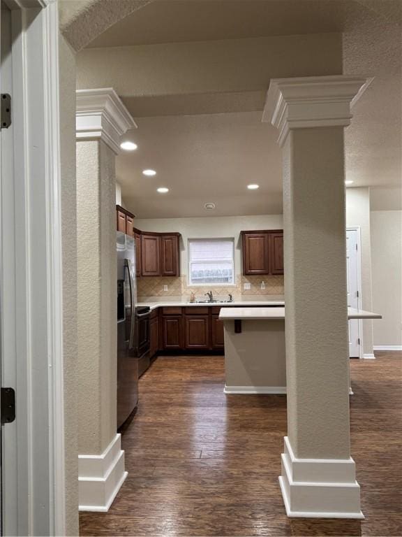 kitchen featuring stainless steel refrigerator with ice dispenser, dark hardwood / wood-style floors, tasteful backsplash, and decorative columns