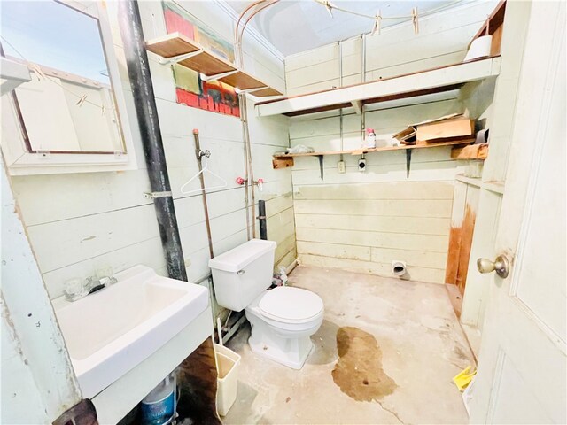 bathroom with concrete flooring, sink, and toilet