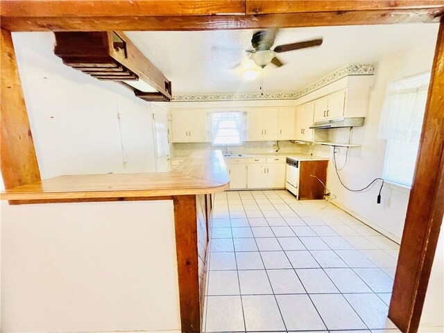 kitchen with white cabinets, kitchen peninsula, sink, light tile patterned flooring, and ceiling fan