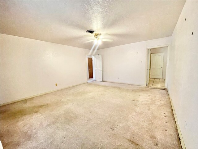 unfurnished room featuring light colored carpet, a textured ceiling, and ceiling fan