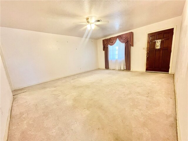 carpeted empty room featuring ceiling fan and a textured ceiling